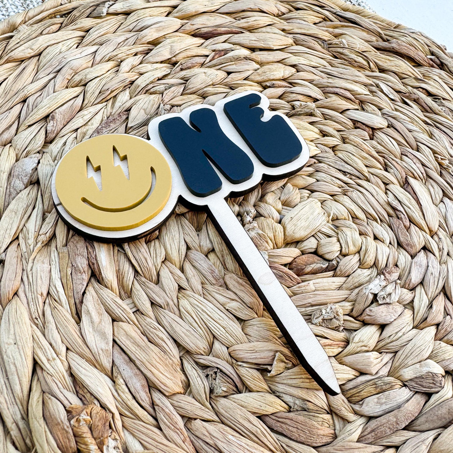 Personalized smiley face first birthday cake topper showing acrylic construction and name