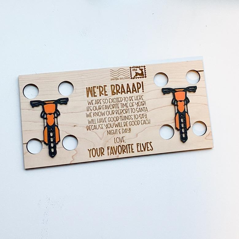 Two elf dirt bike welcome back postcard with two orange bikes and a We're Braaap message from your favorite elves