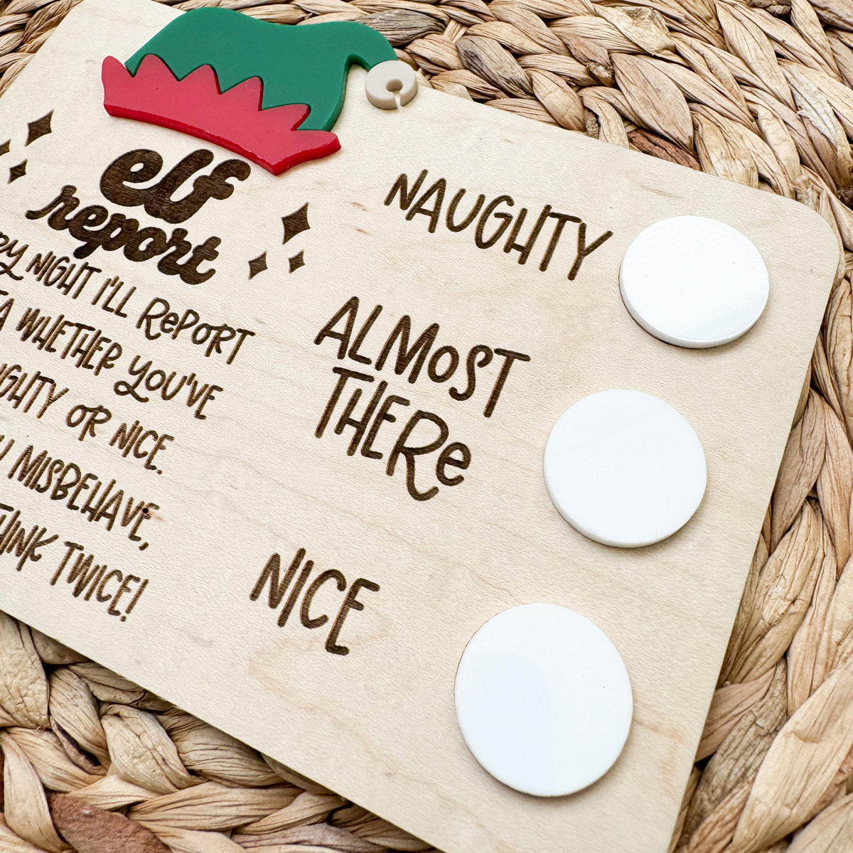 Angled view of the white acrylic dry erase circles beside naughty, almost there and nice on a wooden elf report card