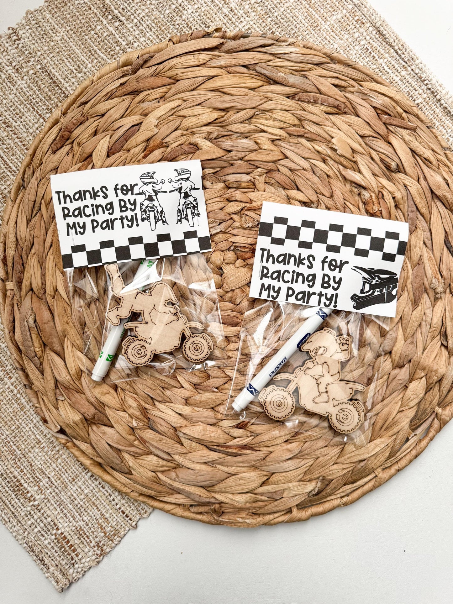 Wooden dirt bike-shaped party favor with “Thanks for Racing By” topper, includes marker and cellophane bag, shown on white background