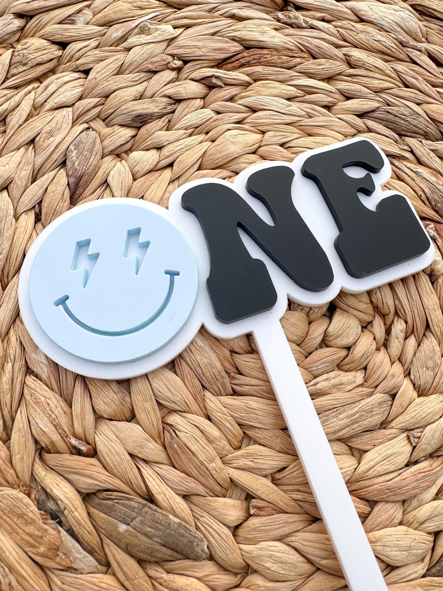 Minimalist ONE smiley cake topper displayed on first birthday smash cake