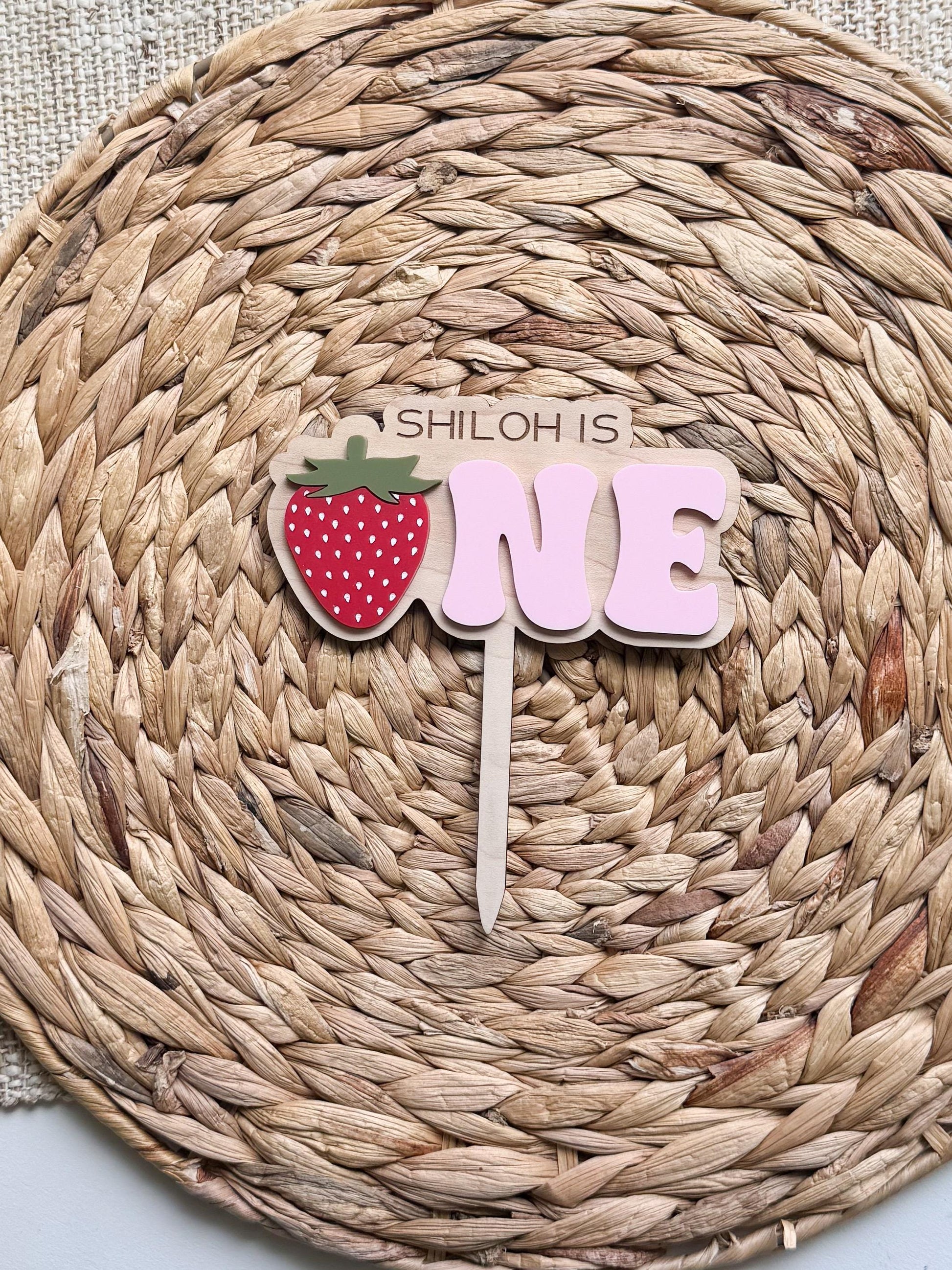 Personalized strawberry first birthday cake topper showing layered acrylic construction