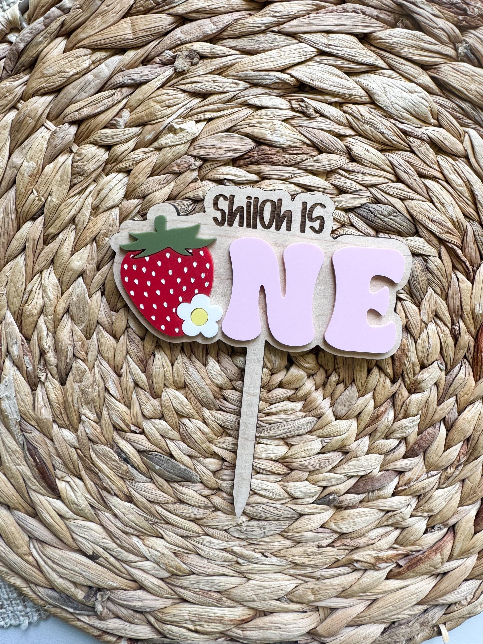 Personalized strawberry first birthday topper displayed on smash cake
