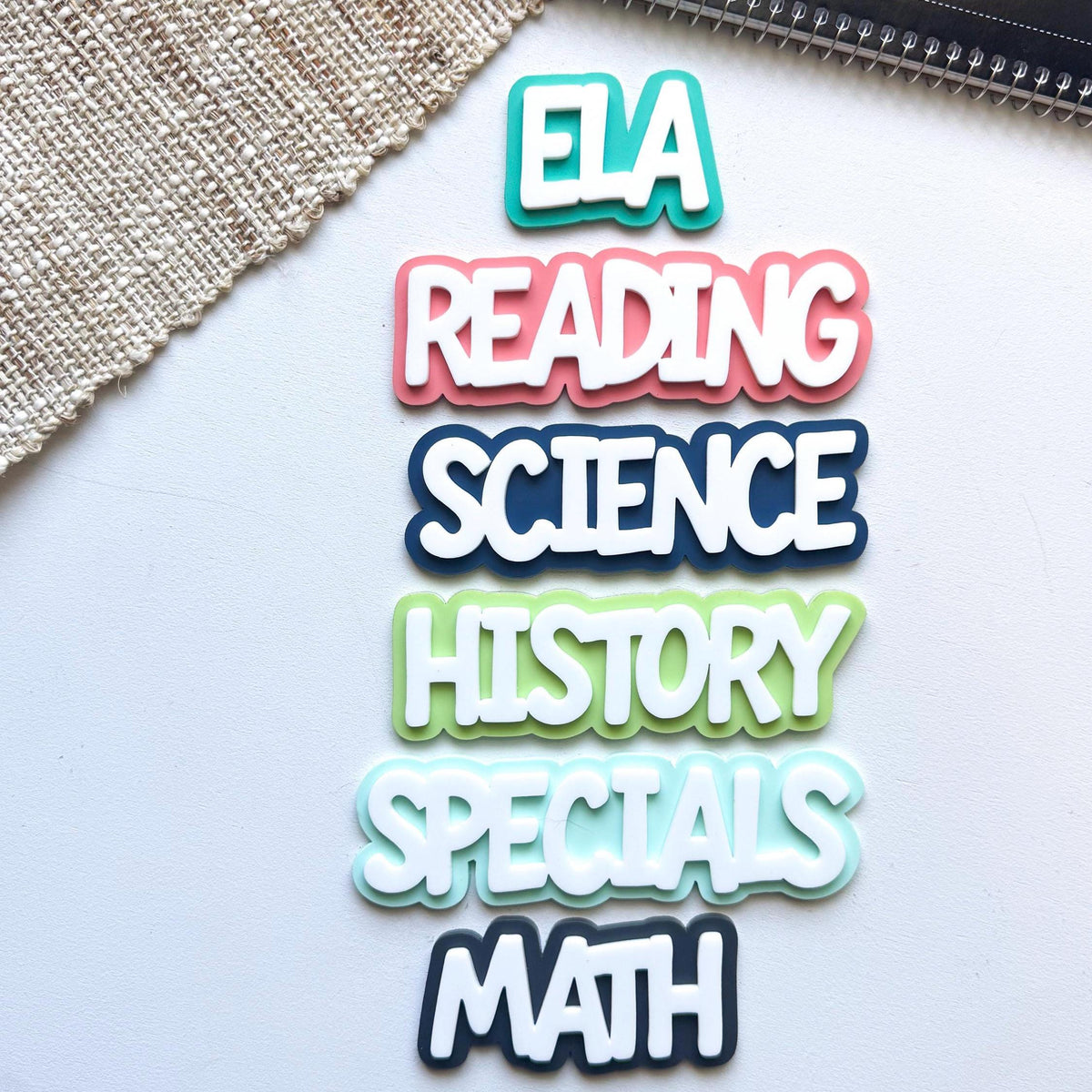 Vertical layout of layered acrylic subject magnets: ELA, Reading, Science, History, Specials and Math in bright colors