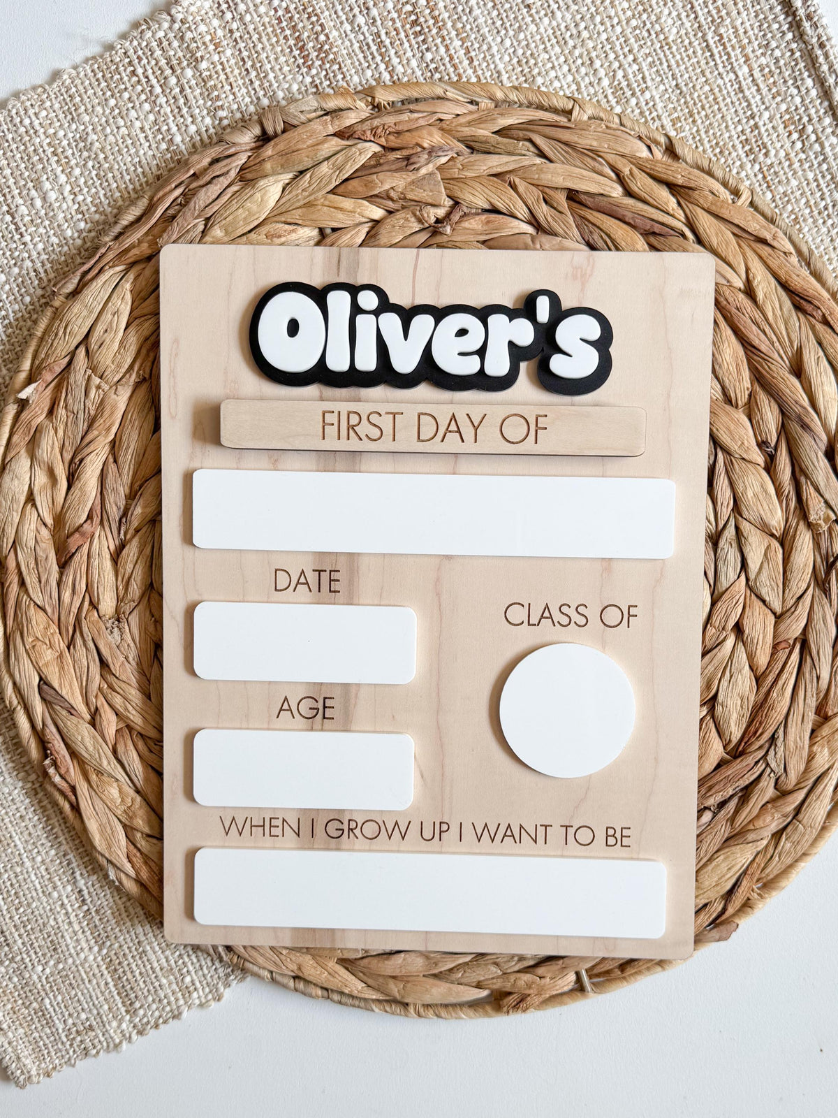 Personalized wooden first day of school sign with layered acrylic name, dry erase writing spaces, interchangeable first and last day plaque, and natural maple finish displayed on a woven mat.