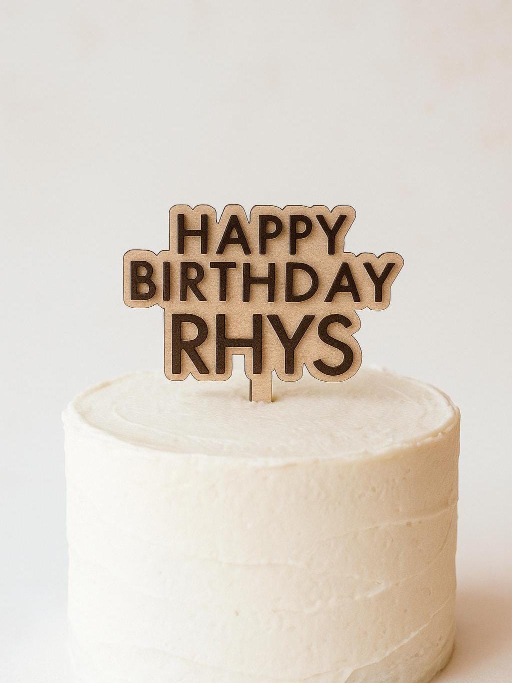 Close-up of personalized Happy Birthday cake topper with custom name and layered design