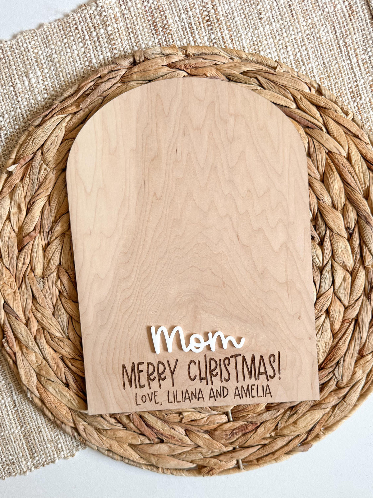 Blank arched maple wood sign with a white acrylic name and engraved Merry Christmas message at the bottom, leaving open space for kids to add their own handprints or footprints
