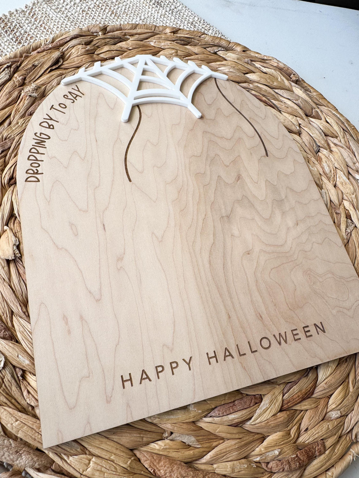 Close angled view of the maple wood Halloween board, showing its natural grain, white acrylic web, and engraved “Happy Halloween” greeting. The unpainted center provides space for handprint spiders.