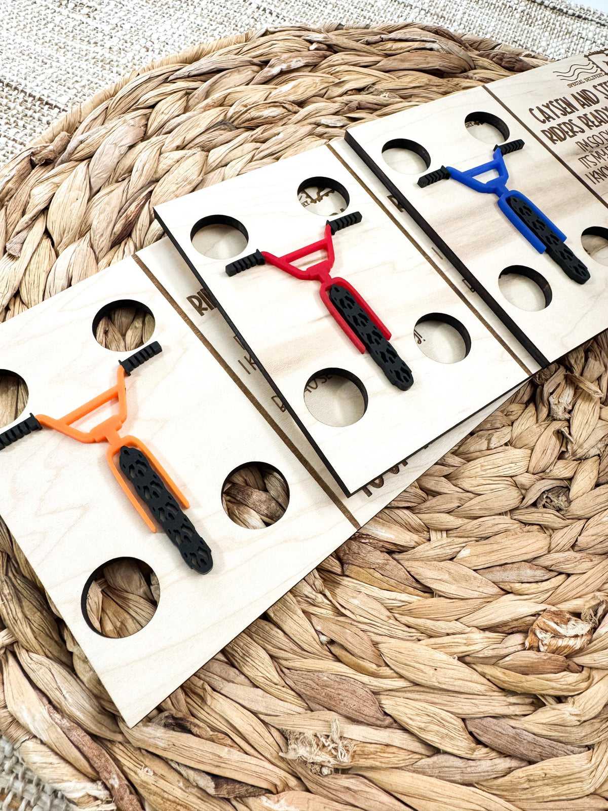 Close-up of orange, red and blue acrylic BMX handlebars and tires with cutouts for the elf's arms and legs