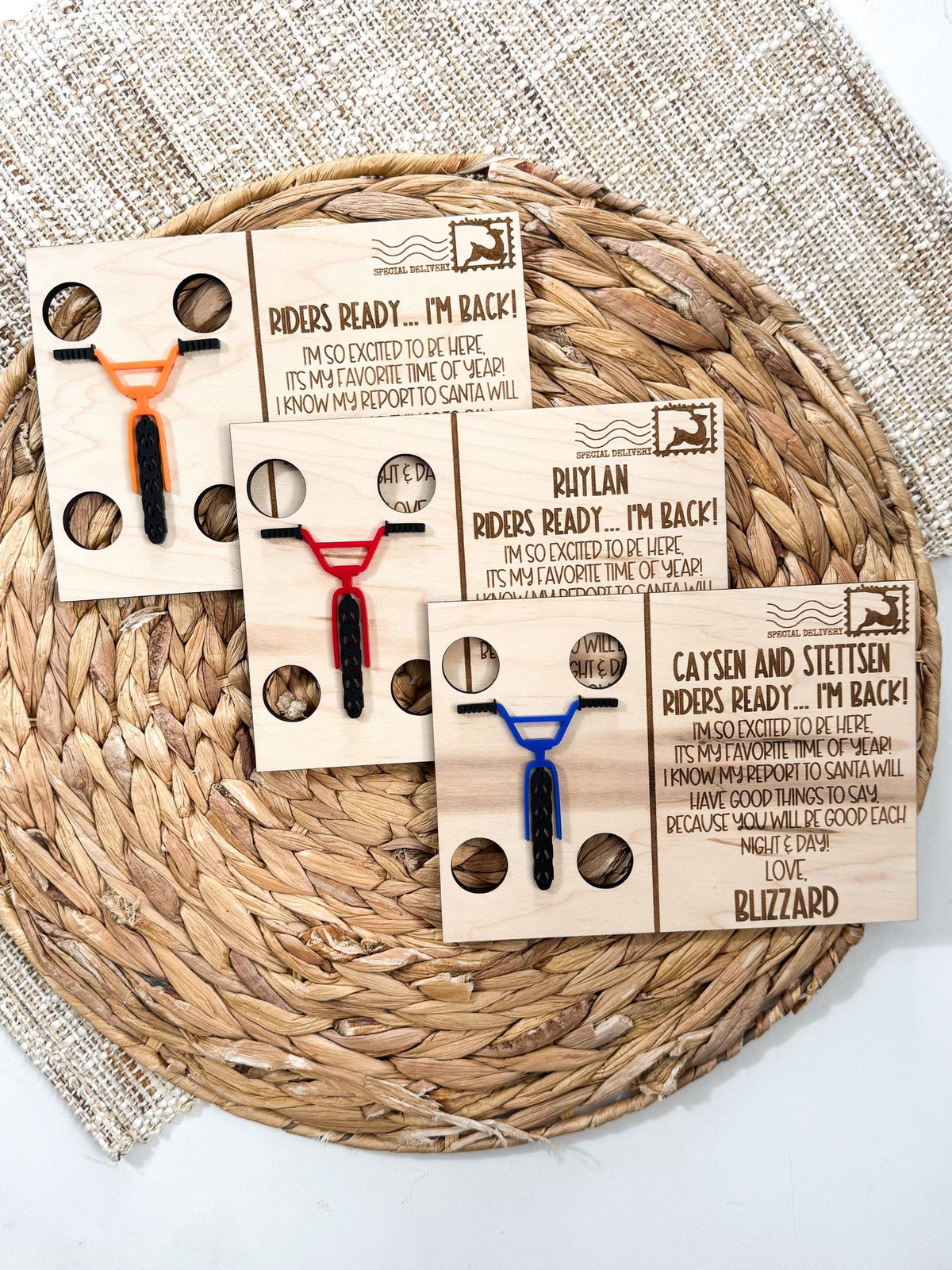 Three personalized BMX elf return postcards in maple wood with orange, red and blue acrylic BMX handlebars and tires