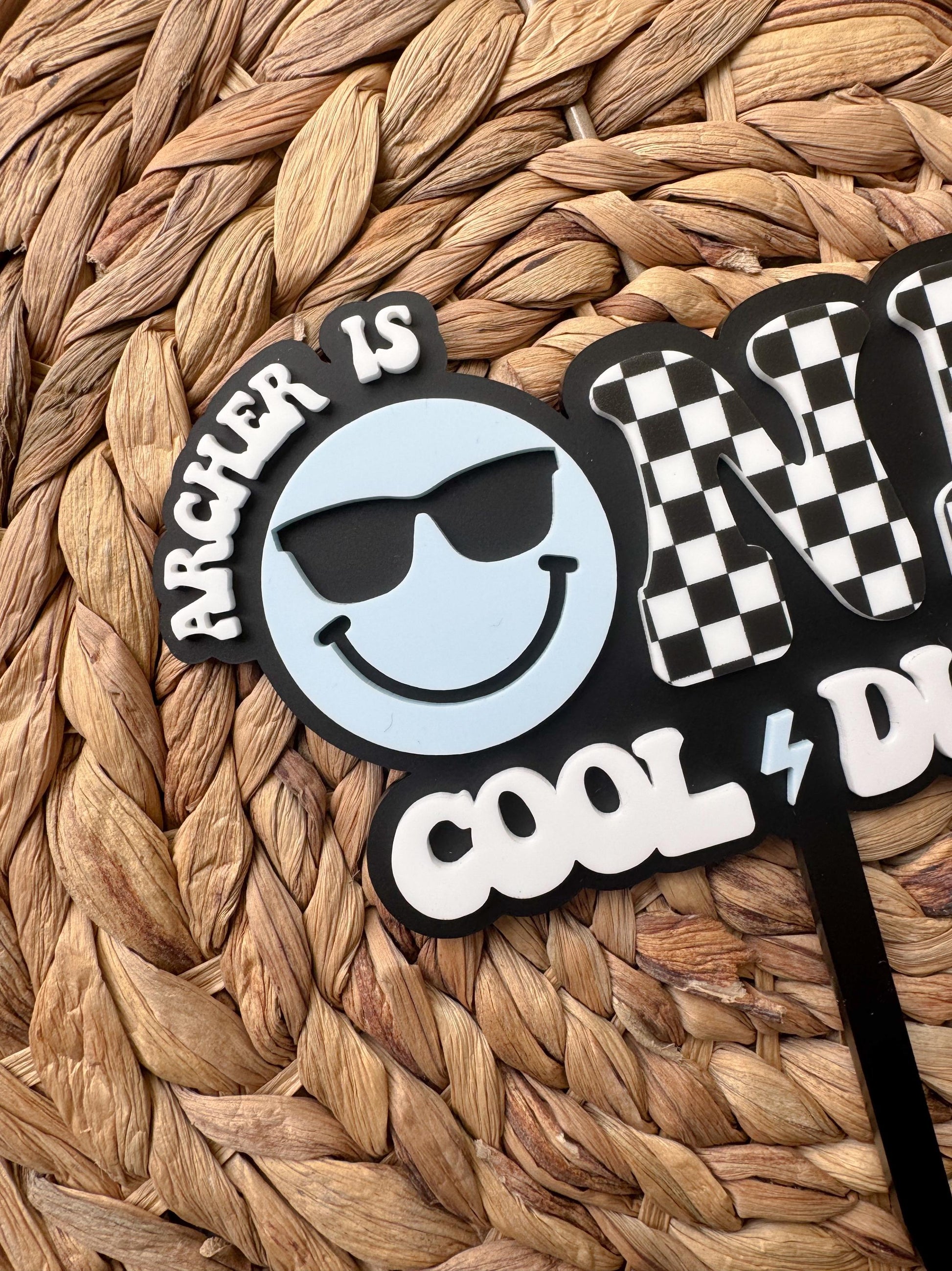 Smiley face cake topper with sunglasses and black white checkerboard ONE lettering