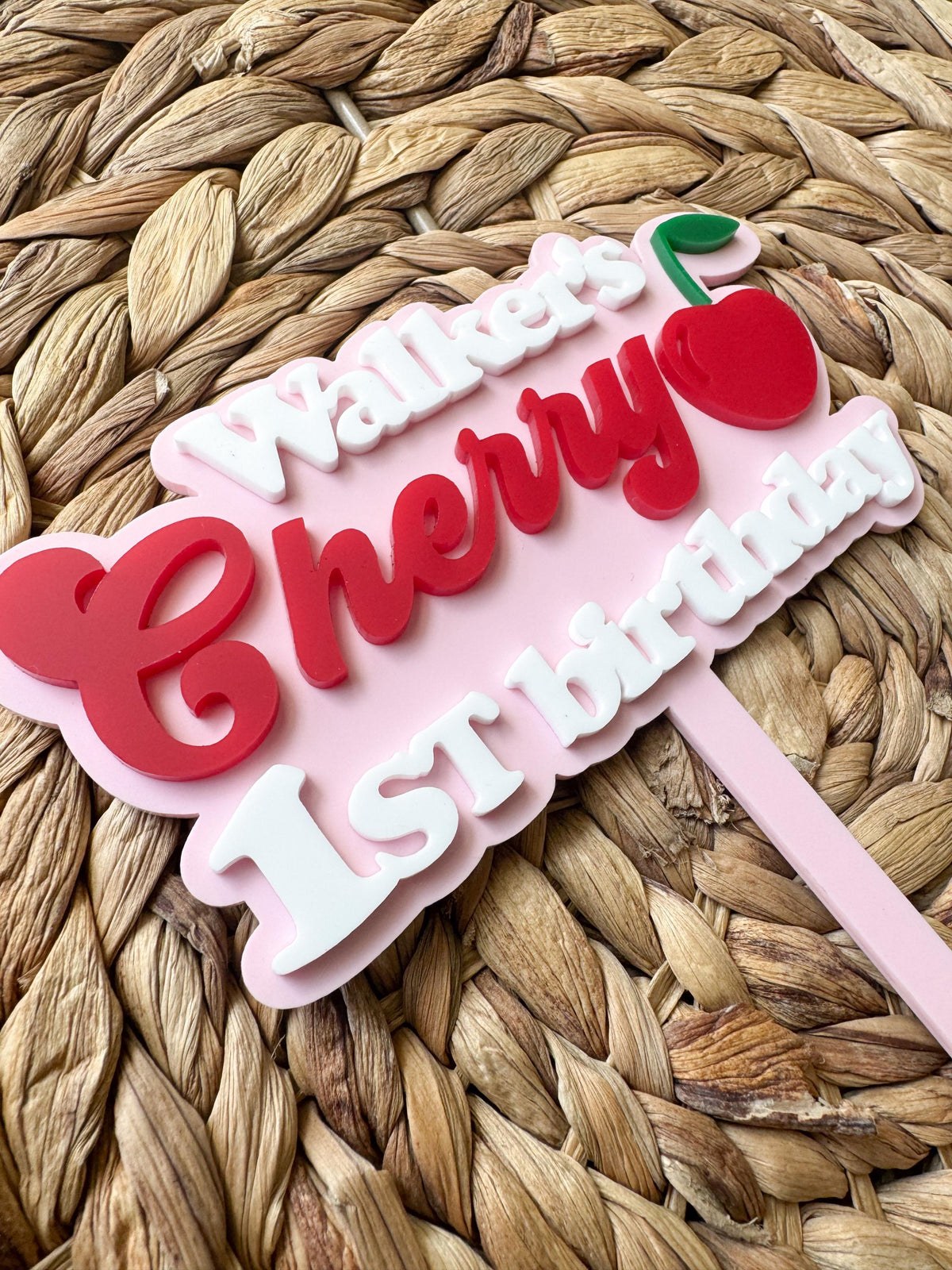 Angled view of personalized One Sweet Cherry cake topper featuring custom name and layered acrylic design.