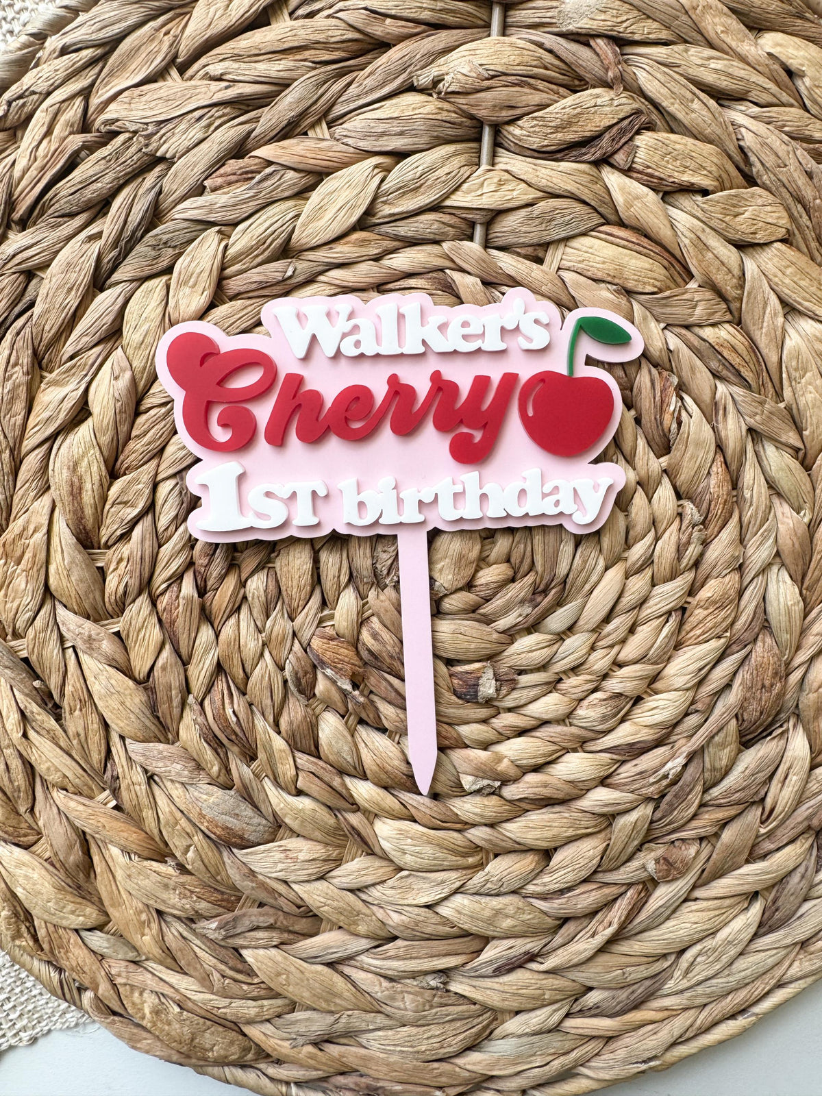 Full product photo of handmade cherry first birthday cake topper with custom name and pink acrylic stake.
