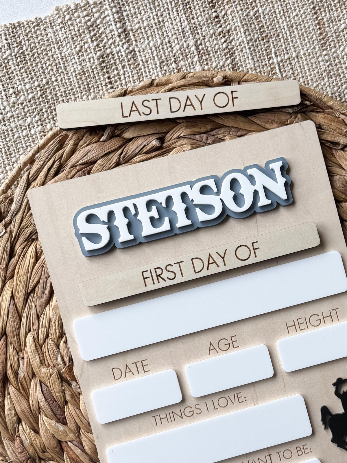 Angled view of personalized school milestone board featuring interchangeable plaques and western bucking horse accent.