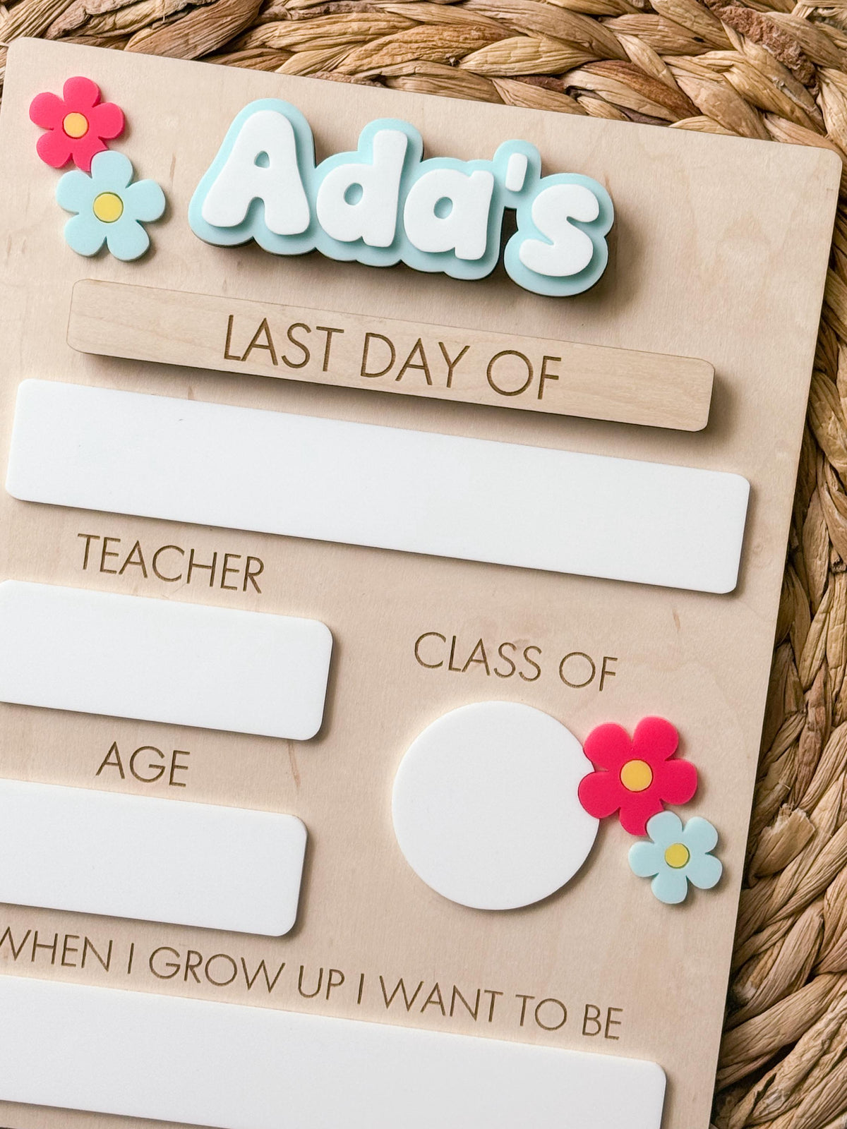 Close-up of personalized daisy school sign with interchangeable Last Day Of piece and dry erase milestone sections.