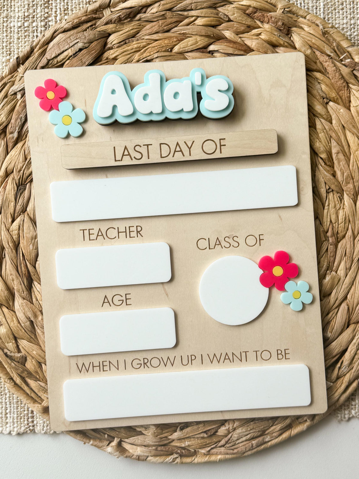 Personalized first day of school board with blue layered name, daisy details and dry erase milestone fields.