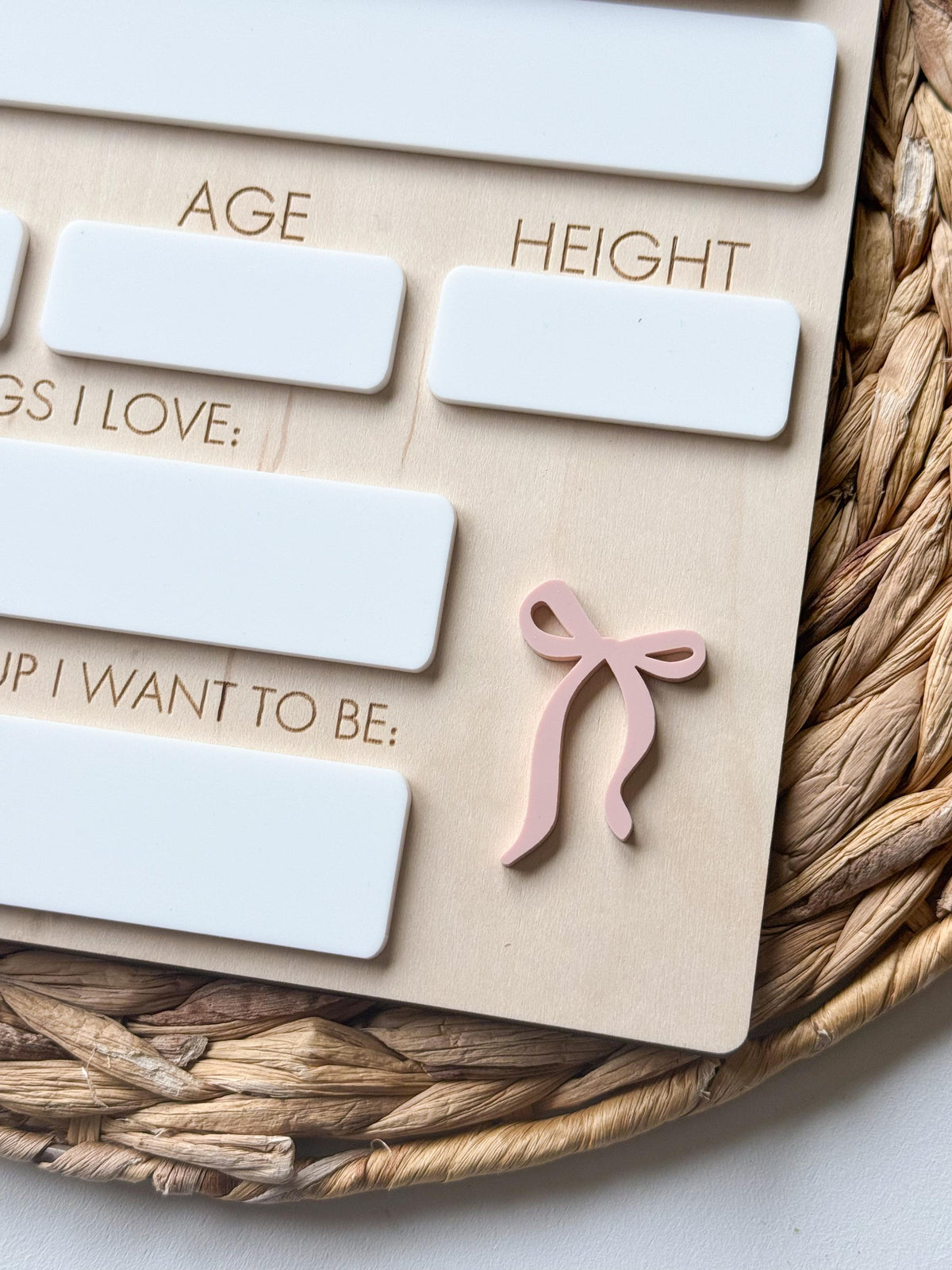 Close-up of decorative pink bow accent on a personalized first day school sign with reusable writing sections.