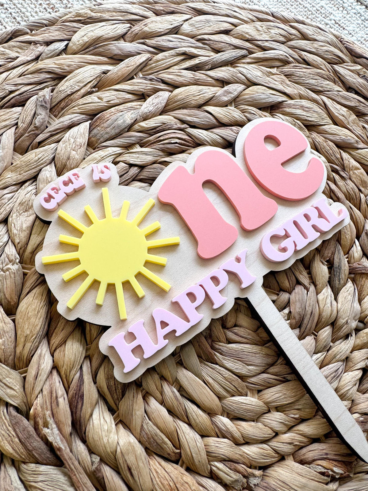 Handmade sunshine first birthday cake topper personalized with child’s name and layered acrylic design.