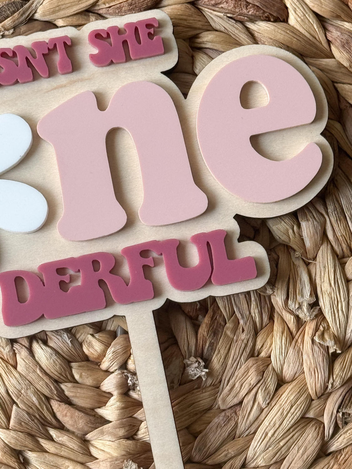 Front view of layered wood and acrylic One-derful birthday cake topper with personalized name.