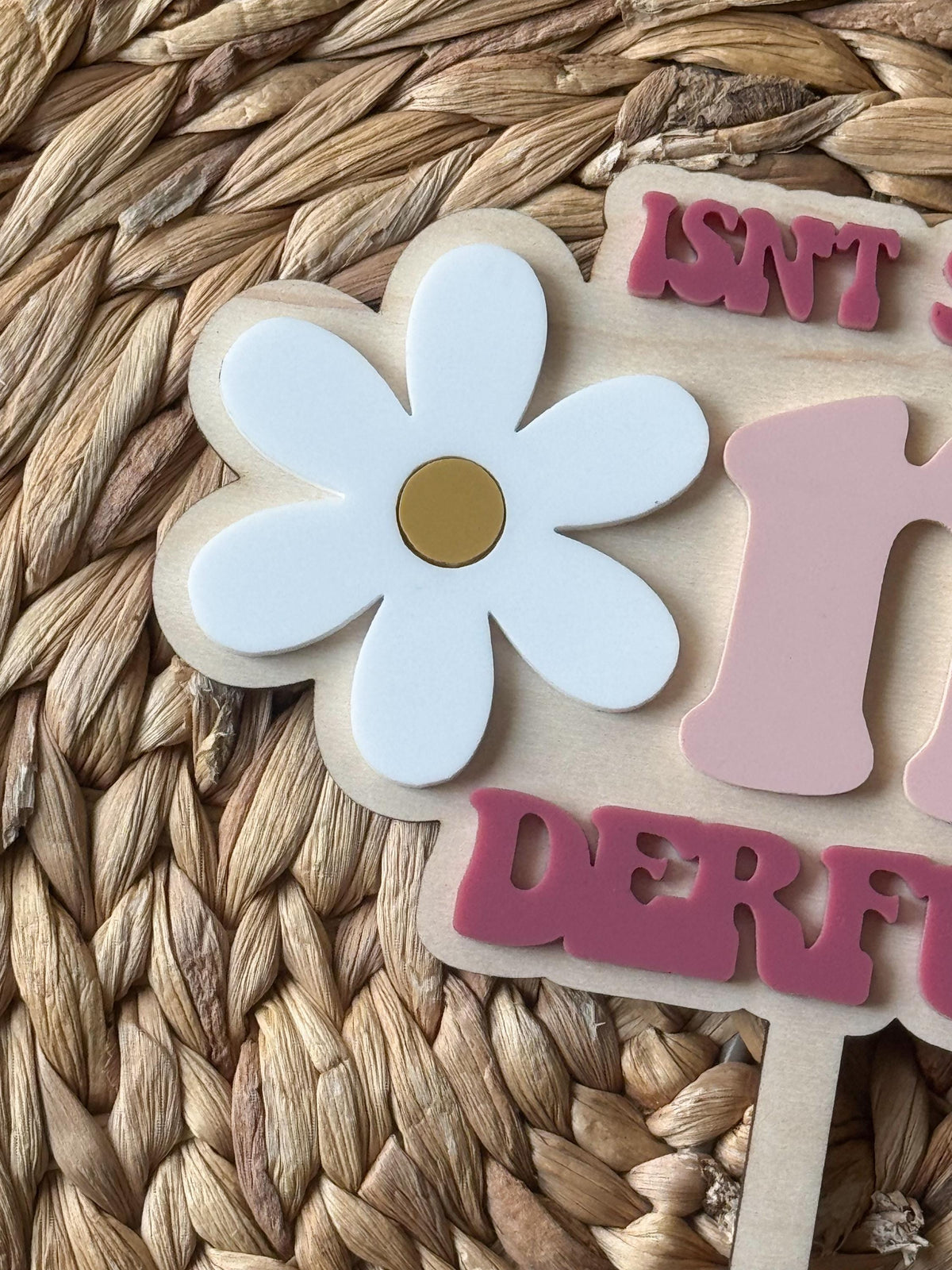 Close-up of personalized One-derful cake topper showing layered daisy flower and custom name detail.
