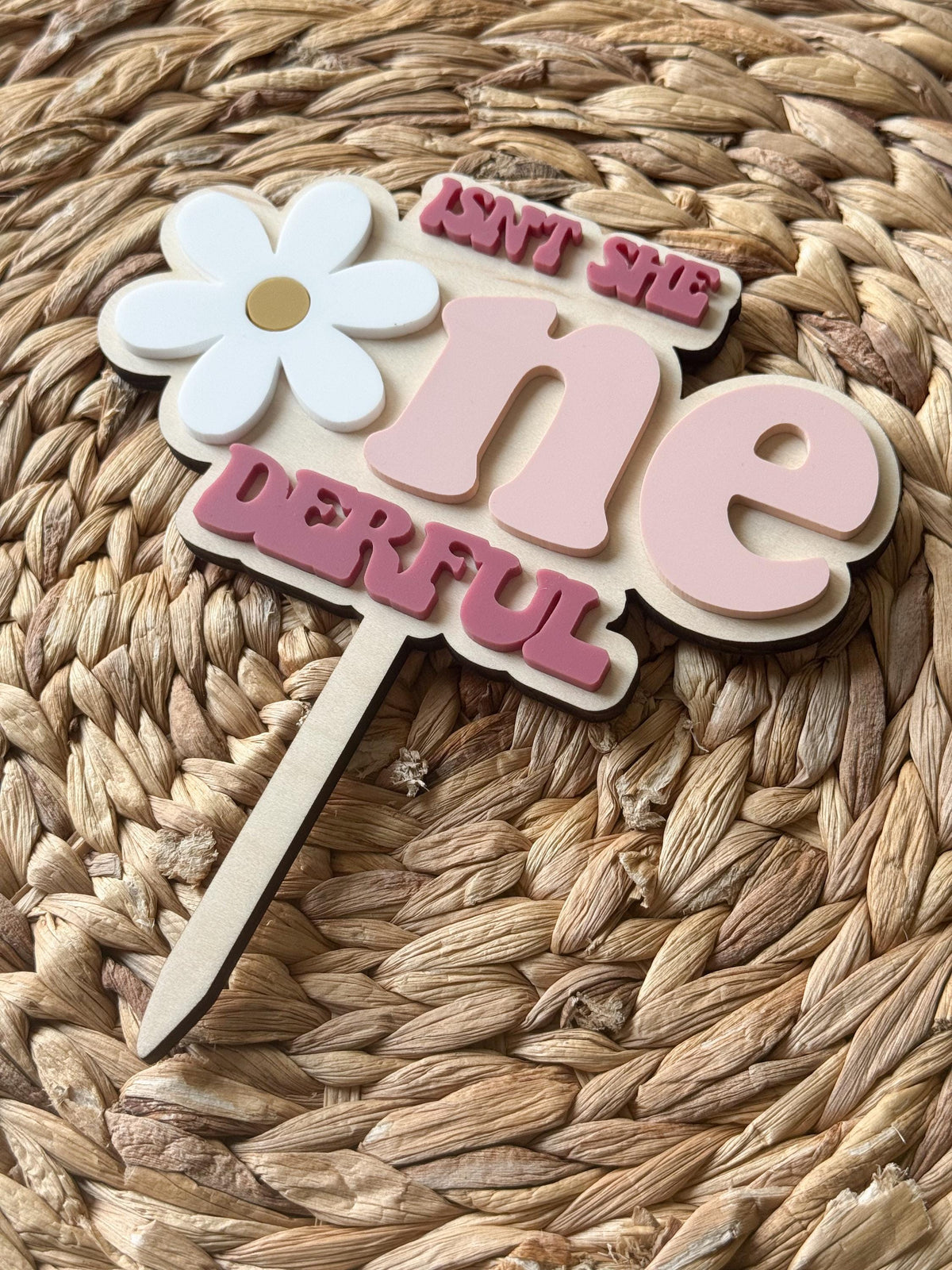 Close-up of layered pink “One-derful” lettering on personalized first birthday cake topper.