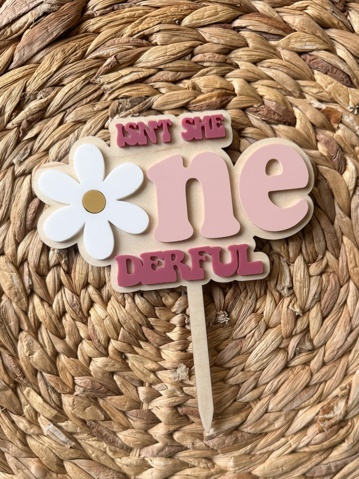Angled view of personalized daisy first birthday cake topper with layered acrylic details.