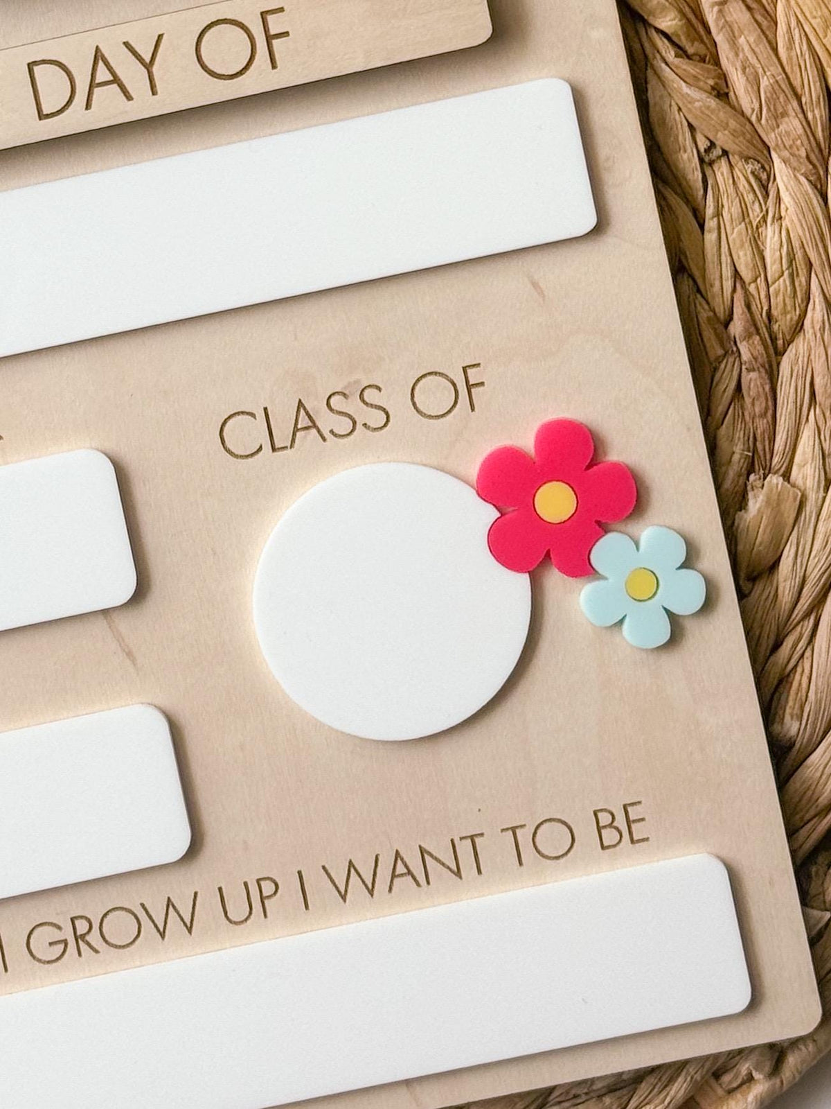 Close-up of daisy school milestone board showing Class Of dry erase section with layered pink and blue flowers.