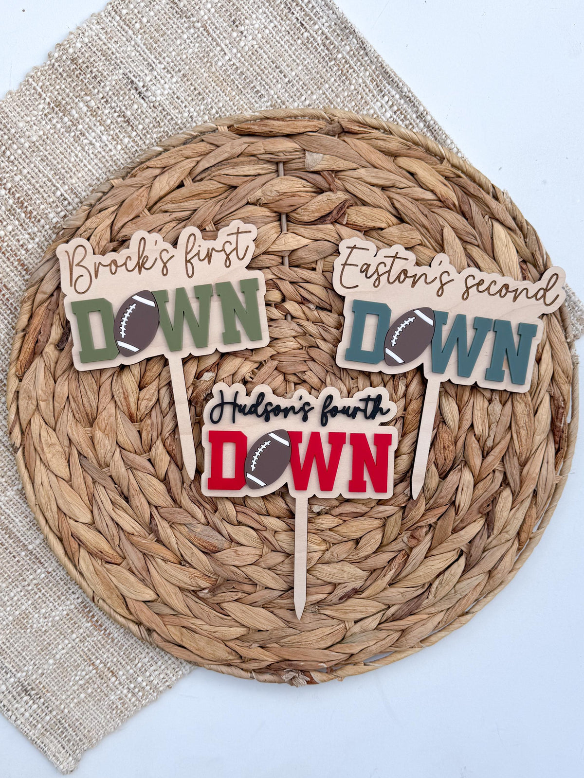 Three personalized football cake toppers in green, teal and red showing First Down, Second Down and Fourth Down, so the design can be made for any birthday age