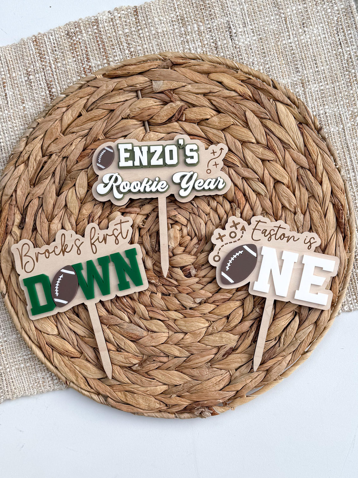 Coordinating football first birthday cake toppers including the First Down topper, a Rookie Year topper and a football ONE topper for a matching party theme