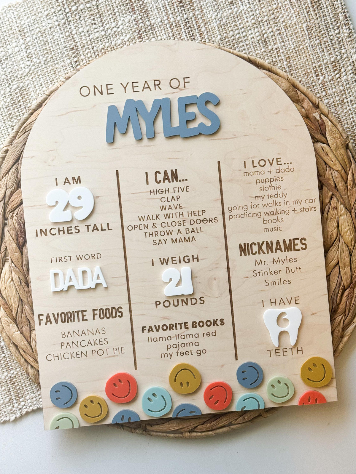 Arched one year milestone sign with white acrylic height and weight numbers, engraved milestones and blue, mustard, coral and sage acrylic smiley faces
