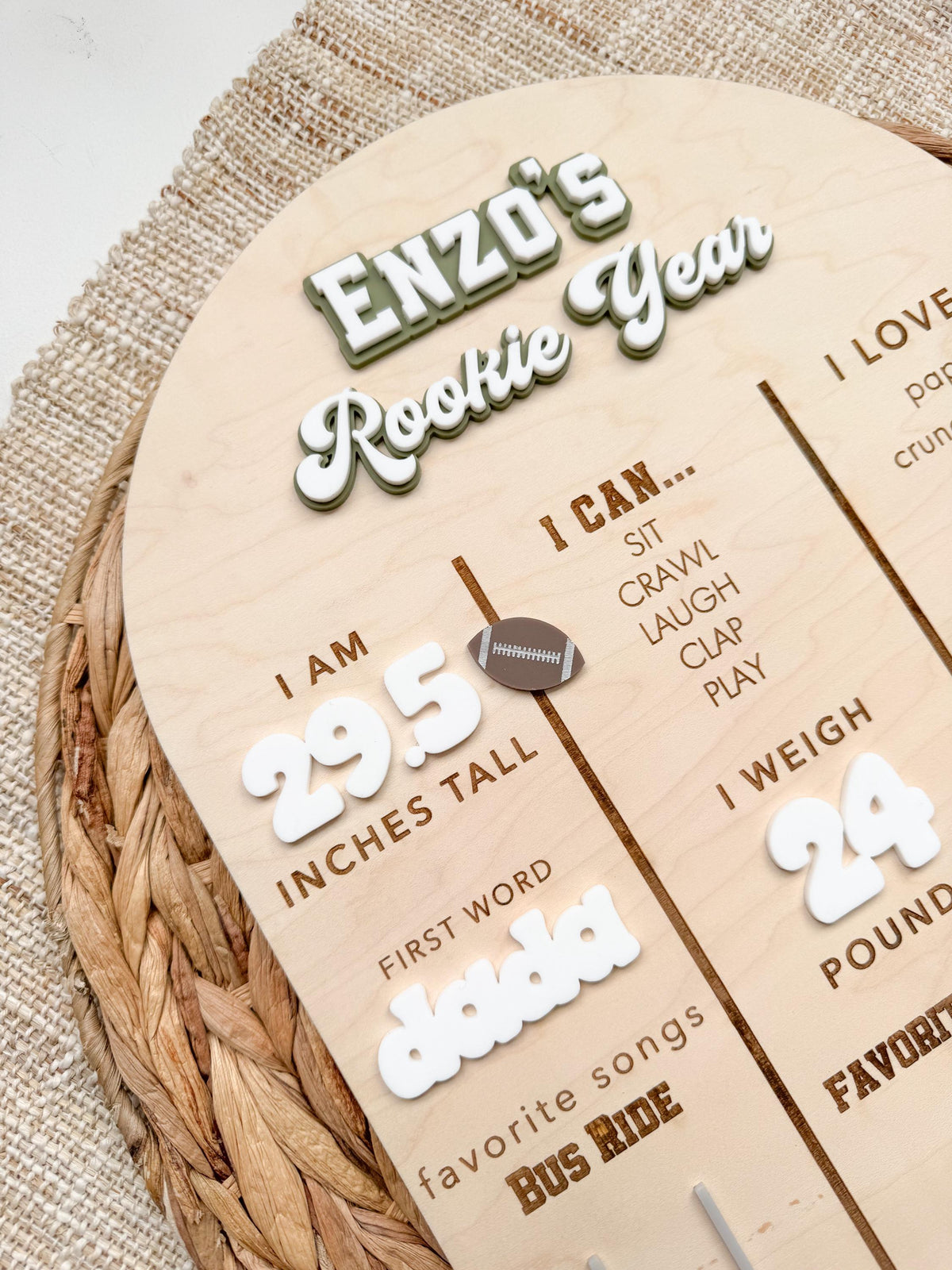 Angled close-up of a personalized Rookie Year milestone board showing the layered acrylic name and retro script title, white acrylic height numbers with a brown football accent, first word in white acrylic and engraved I can list on maple wood