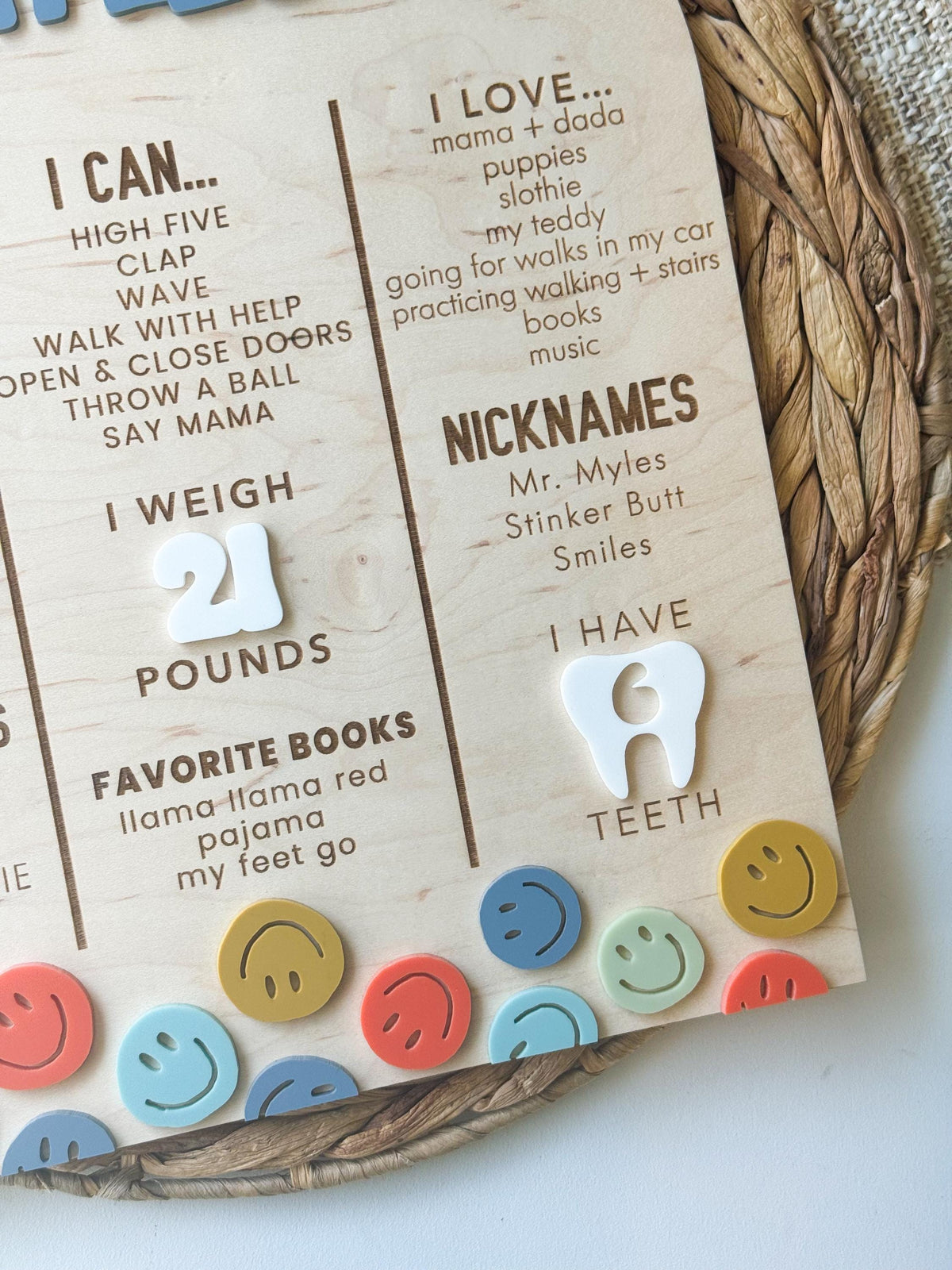 Close-up of white acrylic weight numbers, engraved nicknames and a tooth accent on a smiley face first birthday stat board