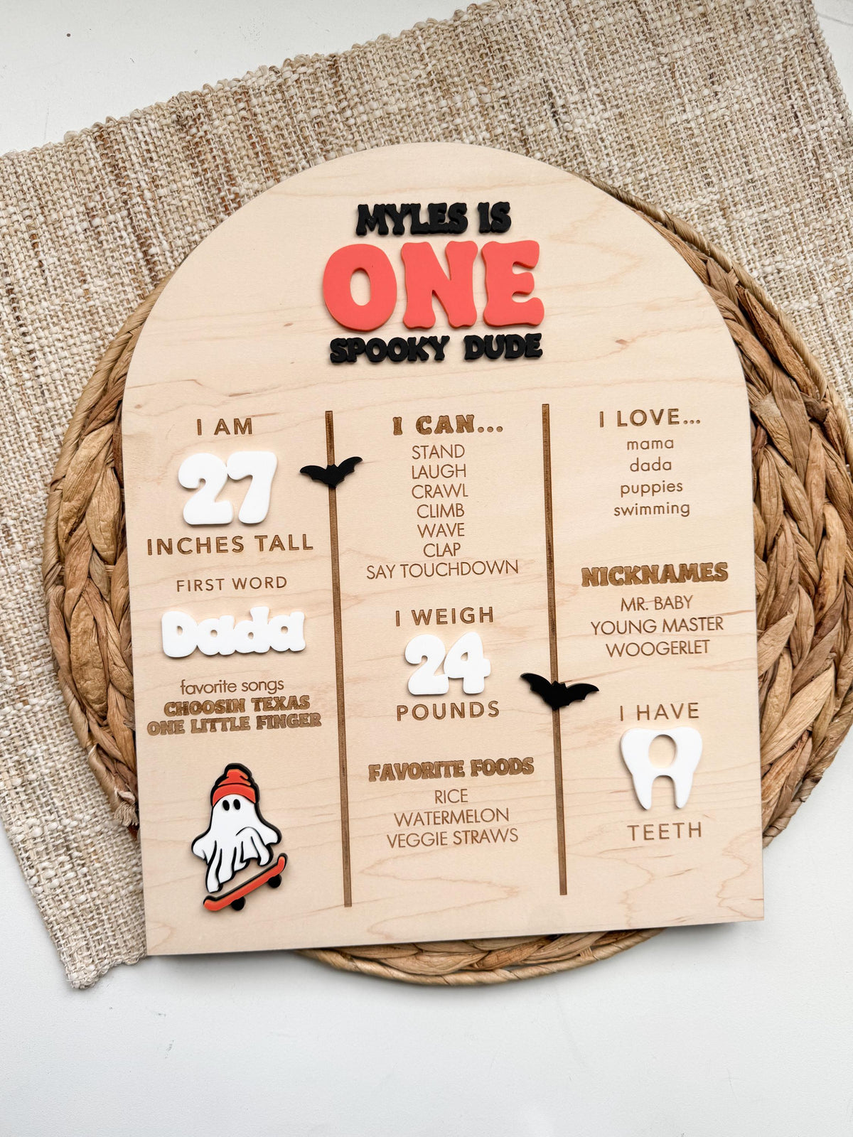Spooky one baby stats sign in natural maple wood with dimensional acrylic lettering, little boo ghost on a skateboard and bat accents, personalized with first year milestones for a Halloween 1st birthday.