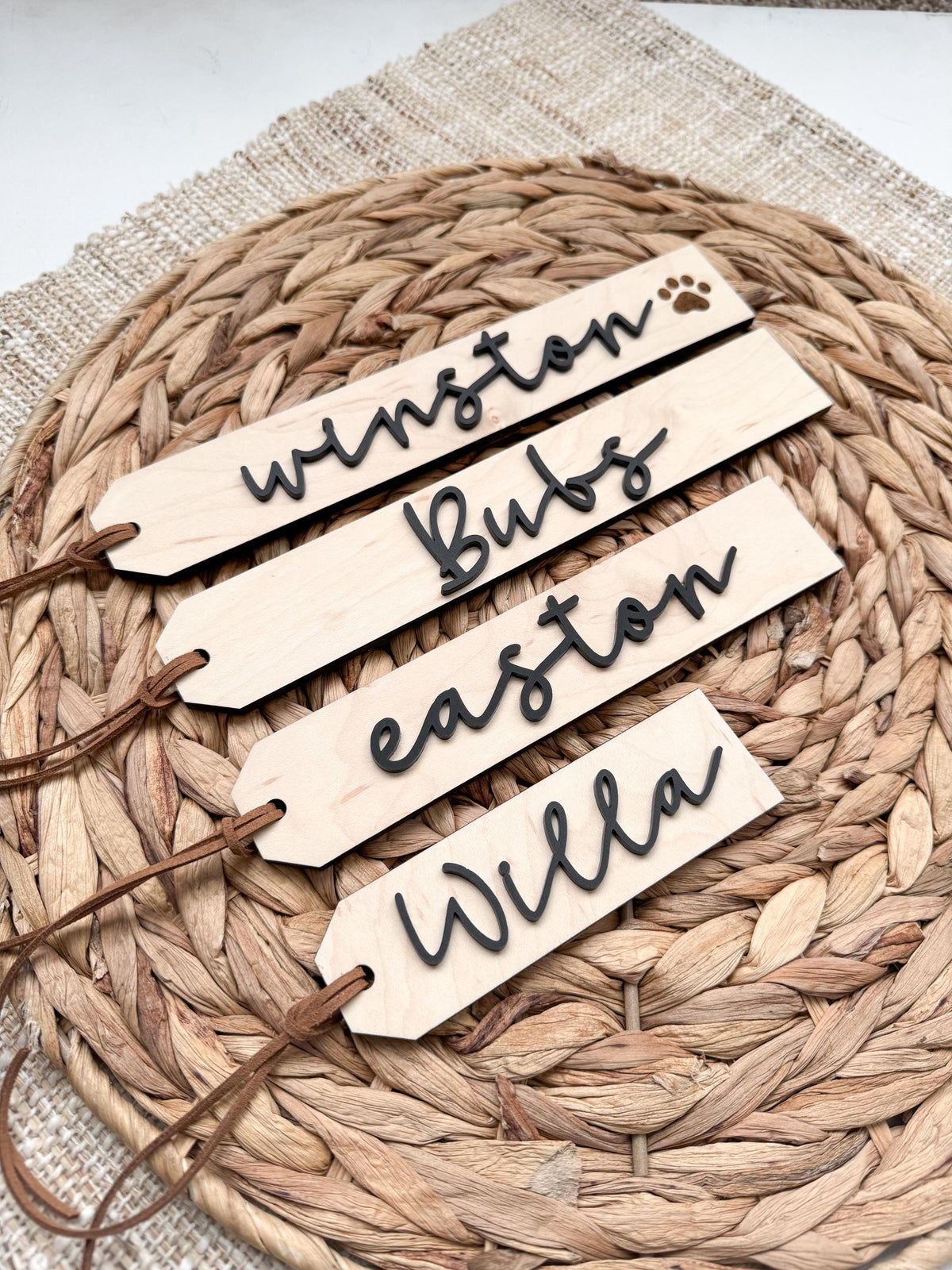 Angled view of custom wooden stocking name tags with script names and a paw print pet tag