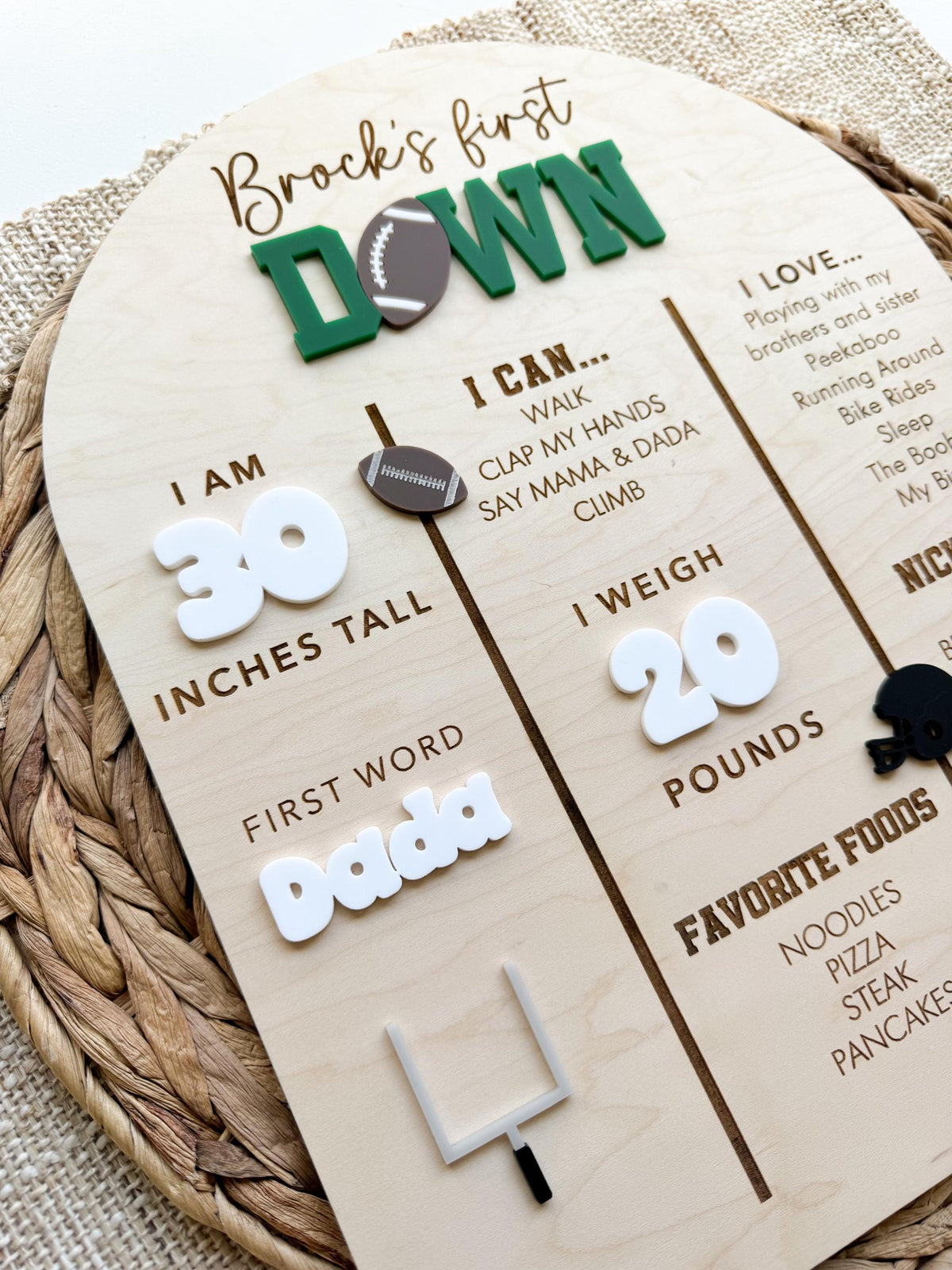 Side angle of a custom First Down birthday milestone board highlighting the layered acrylic title, white acrylic height and weight numbers, white acrylic first word and a gray and black acrylic goal post on engraved maple wood