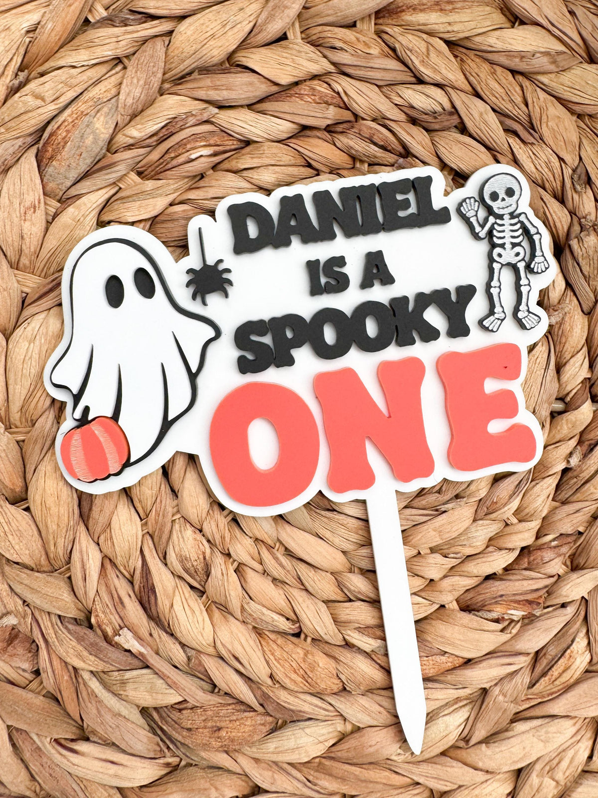 Ghost first birthday cake topper with layered acrylic name and Spooky One lettering on a white backer with attached cake stake, colors customizable.