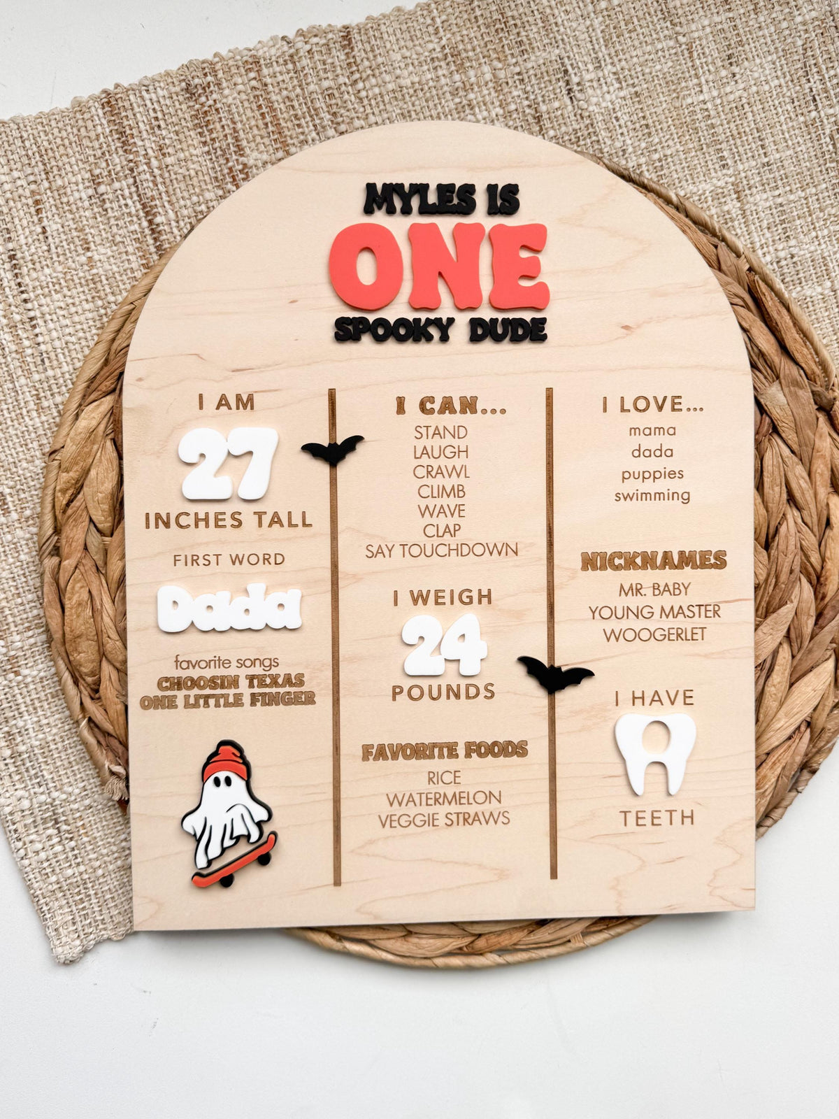 Arched maple wood first birthday stats board with Halloween ghost and bat accents, custom baby height, weight, first word, favorite foods, nicknames and teeth count for a spooky one birthday party.