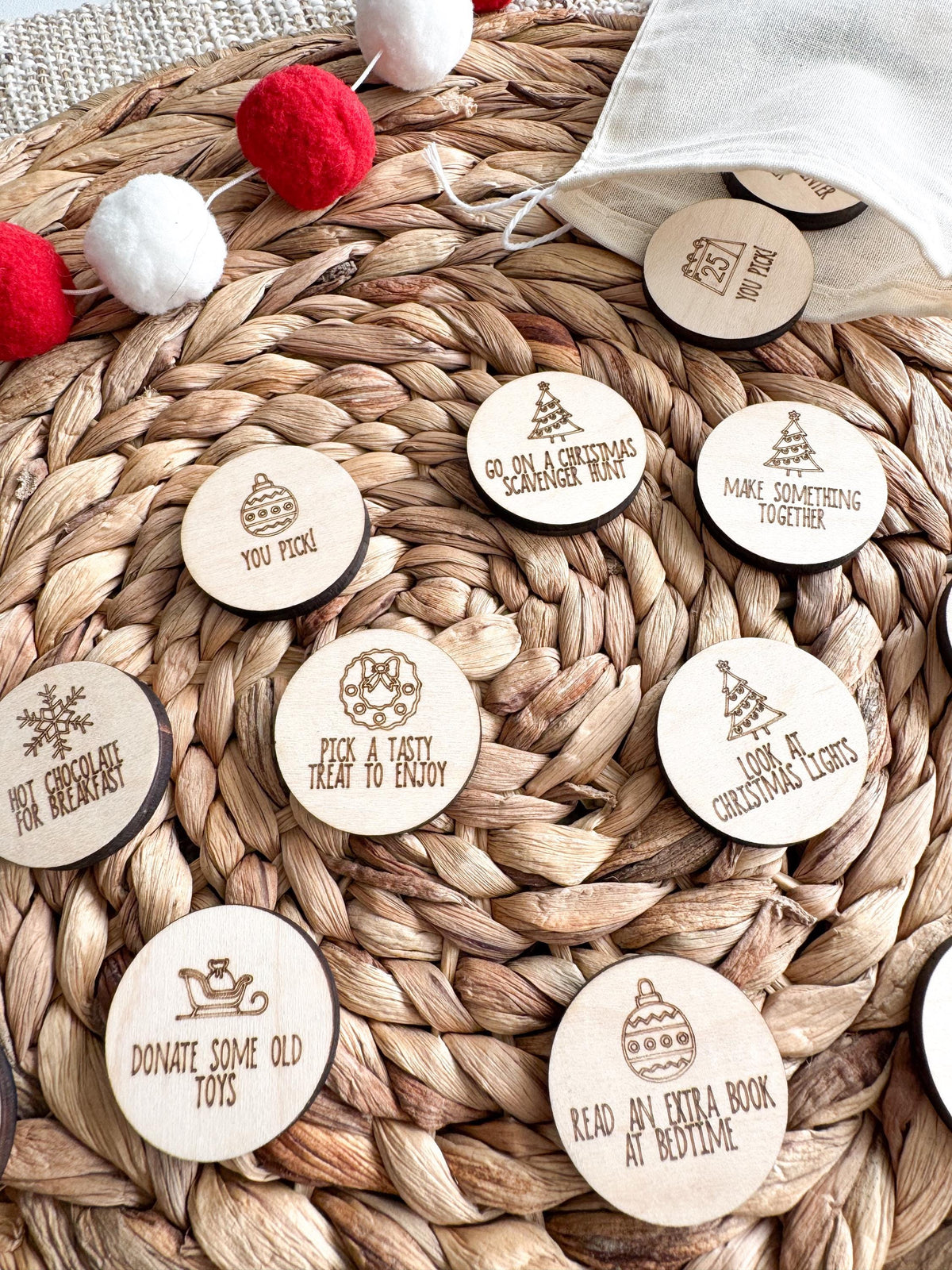 Close-up of 1.5 inch round wooden Christmas activity tokens laser engraved with Pick a Tasty Treat to Enjoy, Donate Some Old Toys and Read an Extra Book at Bedtime. Simple acts of kindness and holiday traditions for an advent calendar.