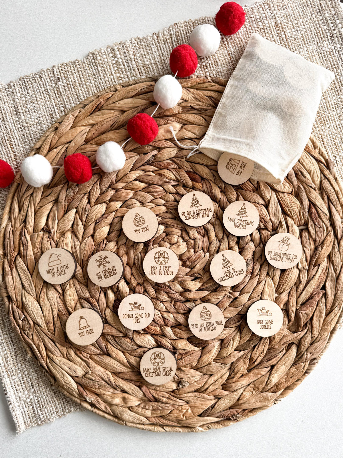 Wooden Christmas activity tokens with a cotton drawstring storage bag, engraved with holiday activities and festive icons like Christmas trees, snowmen and ornaments. A reusable advent calendar set for a family Christmas countdown.