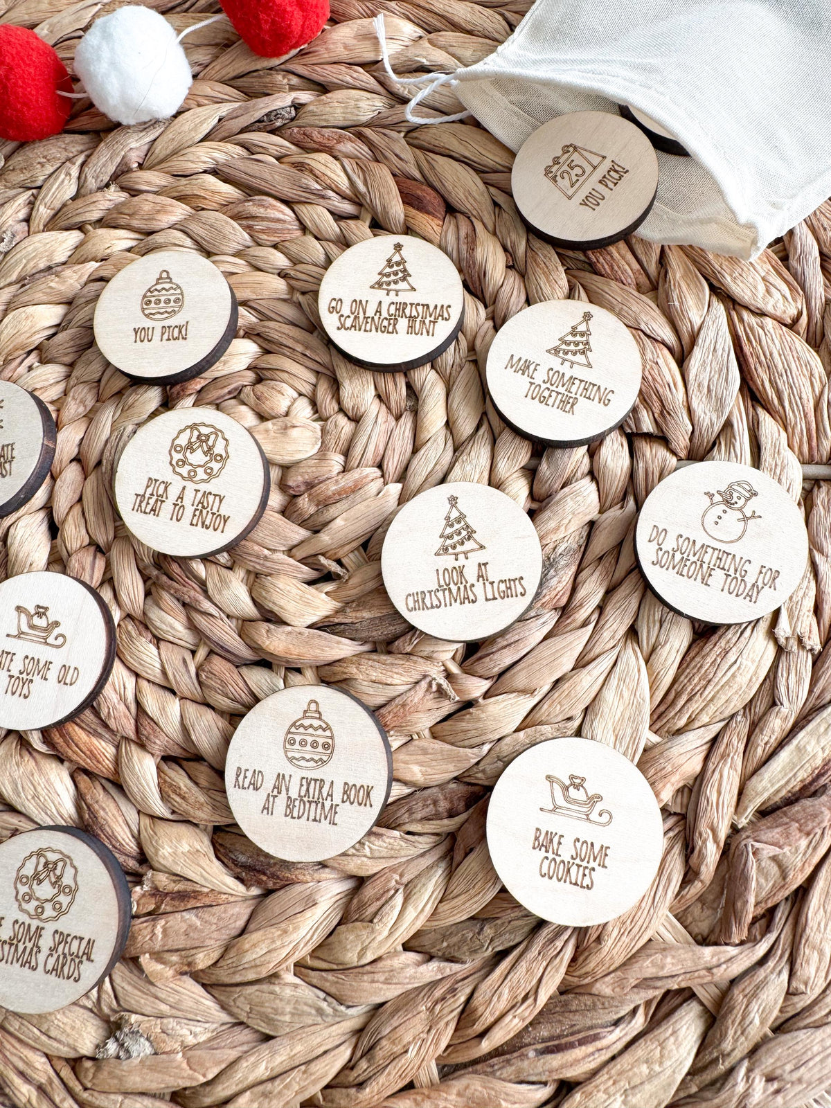 Angled view of engraved maple Christmas activity tokens such as Look at Christmas Lights, Do Something for Someone Today and Bake Some Cookies. Reusable wooden advent coins that make December traditions easy for kids and families.